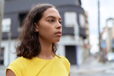 Young african american woman looking to the side with serious expression at street