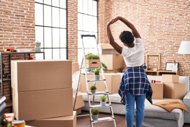 African american woman stretching arms standing on back view at new home