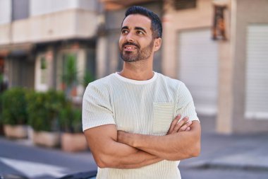 Genç İspanyol adam gülümsüyor. Kendine güveni tam. Sokakta çapraz hareketlerle duruyor.