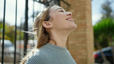 Young blonde woman breathing with closed eyes at street