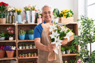 Çiçekçiye elinde bir buket çiçek tutan kır saçlı bir çiçekçi.