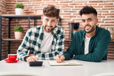 Young couple doing family accounting sitting on table at home