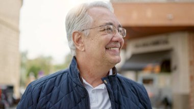 Orta yaşlı, gri saçlı, kendine güveni olan bir adam.