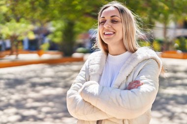 Young woman smiling confident standing with arms crossed gesture at park