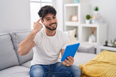 Sakallı İspanyol bir adam kanepeye oturmuş gülümsüyor ve tek parmakla işaret ediyor. Harika bir fikir ya da düşünce, iyi bir hafıza. 