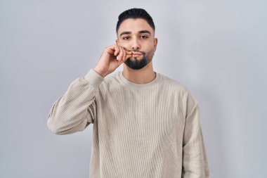 İzole edilmiş arka planın başında duran genç yakışıklı bir adam ağzı ve parmaklarıyla fermuar gibi kapanmış dudakları. gizli ve sessiz, tabu konuşması 