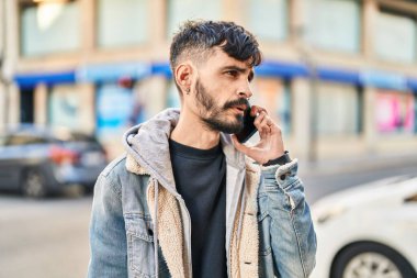 Genç İspanyol adam caddede akıllı telefondan konuşuyor.