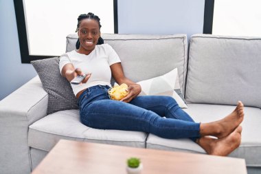 African american woman watching movie sitting on the sofa at home