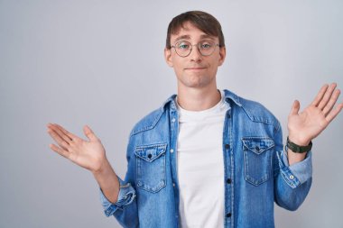 Beyaz, sarışın, gözlüklü, kafası karışmış, elleri ve kolları havada bir adam. şüphe kavramı. 