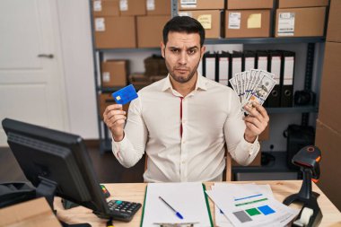 Küçük işletme şirketinde sakallı genç İspanyol bir adam elinde banknotlar, kredi kartı tutuyordu şüpheci ve gergindi, sorun yüzünden surat asıyordu. negatif kişi. 
