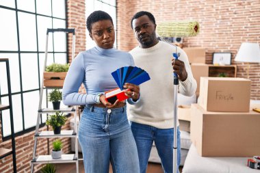 Genç Afro-Amerikan çifti yeni bir eve taşınıyor duvarları seçiyor şüpheci ve gergin renkler, sorun yüzünden somurtuyorlar. negatif kişi. 