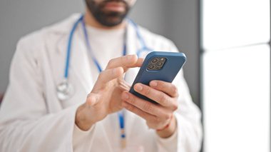 Genç İspanyol doktor klinikte akıllı telefon kullanıyor.