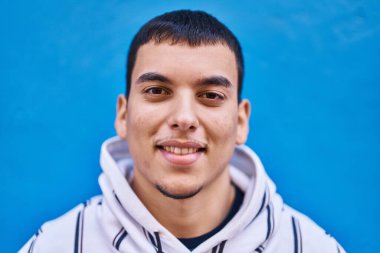 Mavi arka planda duran kendine güvenen genç adam.