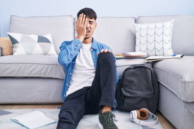 Genç İspanyol bir adam yerde oturmuş üniversite için çalışıyor. Yarı yüzünü, göz ve ağzını eliyle kapatmaktan yoruluyor. Yüzüm acıyor.. 