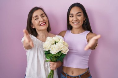 İspanyol anne ve kızı ellerinde bir buket beyaz çiçekle dostça el sıkışarak selamlaşıyorlar. başarılı iş. 