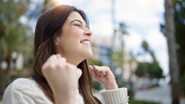 Genç ve güzel İspanyol kadın gülümsüyor. Kazanan yüz ifadesiyle caddede duruyor.