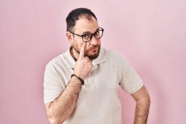 Artı, pembe arka planda sakallı İspanyol bir adam. Gözünü dikip jestini izliyor. Şüpheli bir ifade. 