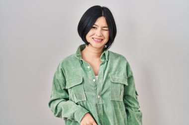 Beyaz arka planda duran genç Asyalı kadın kameraya seksi bir ifadeyle bakıyor, neşeli ve mutlu bir yüzle.. 