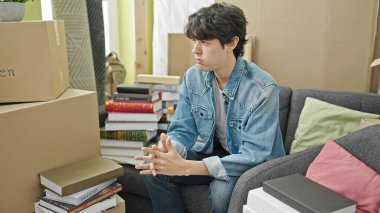 Yeni evindeki kanepede oturan genç İspanyol stresli adam.