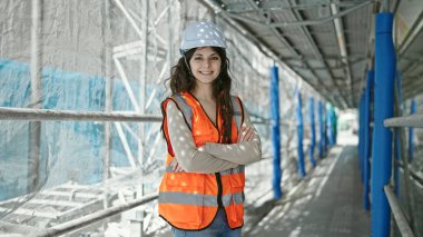 Güzel İspanyol kadın mimar gülümsüyor. Kollarını kavuşturup caddede duruyor.