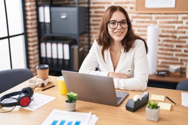 Ofiste çalışan genç bir iş kadını dizüstü bilgisayar kullanıyor.