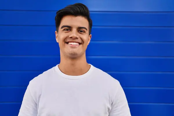 Joven Hombre Hispano Sonriendo Confiado Pie Sobre Aislado Fondo Azul —  Fotos de Stock