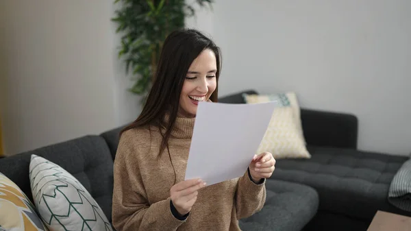 stock image Beautiful hispanic woman reading document sitting on sofa at home