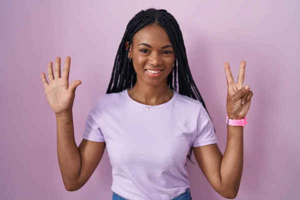 Африканская Американка Косичками Стоящая Розовом Фоне Показывающая Пальцами Номер Семь — стоковое фото