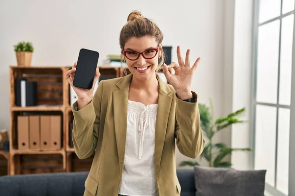 컨설팅 사무실에서 일하고 스마트폰을 손가락으로 보이는 수화를 다정하게 미소를 있습니다 — 스톡 사진