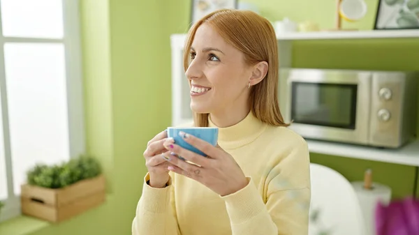 年轻的金发女人坐在家里的桌子上喝咖啡 — 图库照片