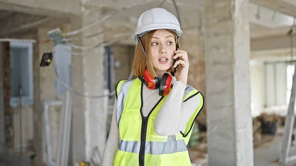 若いブロンドの女性建築家が建設現場でスマートフォンで話しています — ストック写真