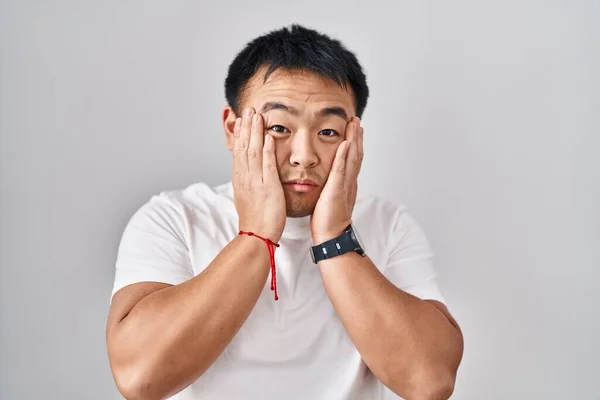 若い中国人男性が白い背景に立って疲れ手を顔 うつ病や悲しみ 動揺し 問題のためにイライラ — ストック写真