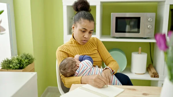 Μητέρα Και Γιος Γράφοντας Σημειώσεις Ενώ Μωρό Θηλάζει Στην Τραπεζαρία — Φωτογραφία Αρχείου
