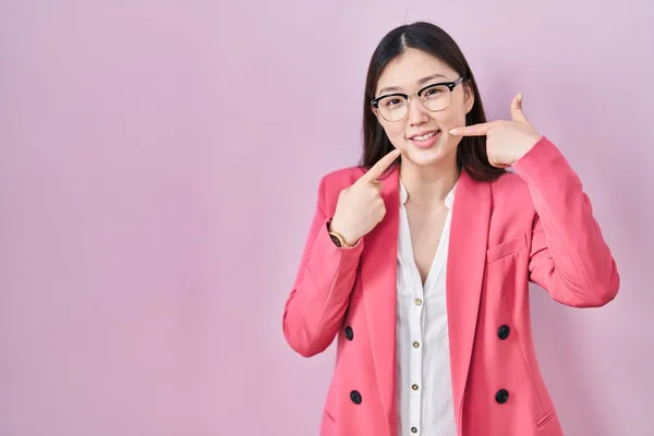 中国のビジネスの若い女性が明るい笑顔を見せ 指の歯と口で指して眼鏡をかけて 歯の健康の概念 — ストック写真