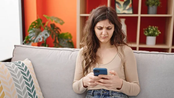 年轻美丽的惊慌失措的女人用智能手机在家里烦躁不安 — 图库照片
