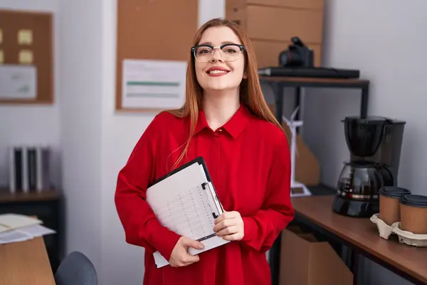 若いです赤毛女性ビジネスワーカー笑顔自信を持って保持クリップボードでオフィス — ストック写真