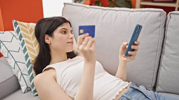 Young Beautiful Hispanic Woman Shopping Smartphone Credit Card Lying Sofa — Stock Photo, Image