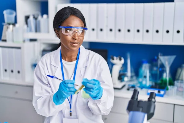 若いアフリカ系アメリカ人女性科学者が実験室で試験管に書いている — ストック写真