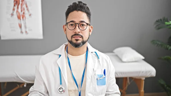 Mladý Latinskoamerický Lékař Sedí Stole Vážným Výrazem Klinice — Stock fotografie