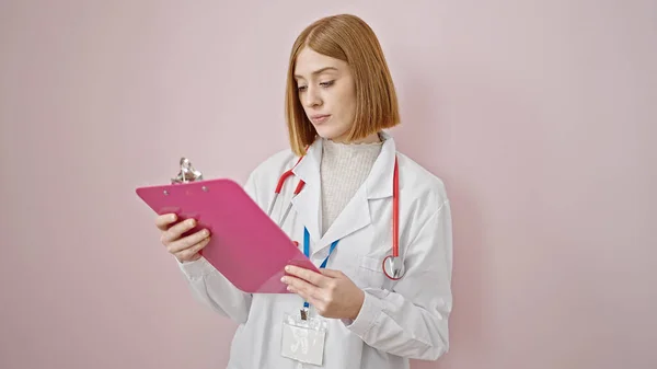 Mladá Blondýna Žena Lékař Čtení Dokumentu Schránce Nad Izolované Růžové — Stock fotografie
