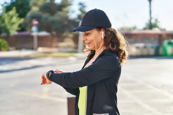 Middle Age Hispanic Woman Working Out Smart Watch Outdoors — Stockfoto