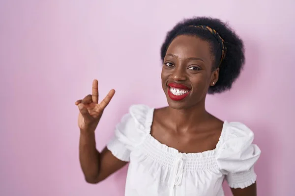 Afrykanka Kręconymi Włosami Stojąca Nad Różowym Tłem Uśmiechnięta Aparatu Pokazującego — Zdjęcie stockowe