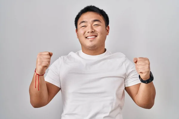 白い背景の上に立っている若い中国人男性は 腕を上げて目を閉じて成功に驚いて驚いています 勝者のコンセプト — ストック写真