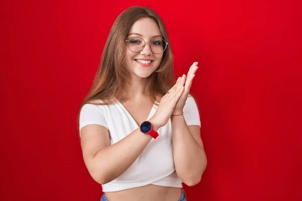 Młoda Biała Kobieta Stojąca Nad Czerwonym Tłem Klaskając Oklaskując Szczęśliwe — Zdjęcie stockowe