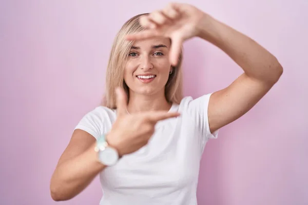 Young Blonde Woman Standing Pink Background Smiling Making Frame Hands — Stock Photo, Image