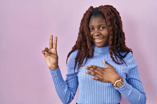 Mujer Africana Pie Sobre Fondo Rosa Sonriendo Jurando Con Mano —  Fotos de Stock