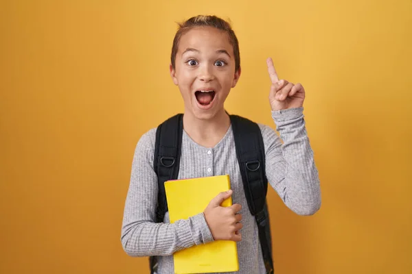 小高加索男孩背着学生背包 拿着一本书 满脑子都是满脸喜色的手指或问答题 位居第一 — 图库照片