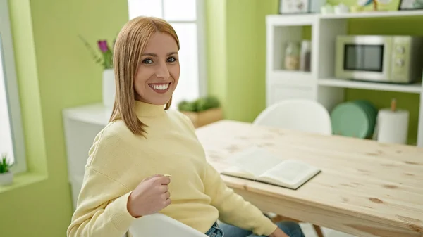 Young Blonde Woman Reading Book Sitting Table Home — Stockfoto