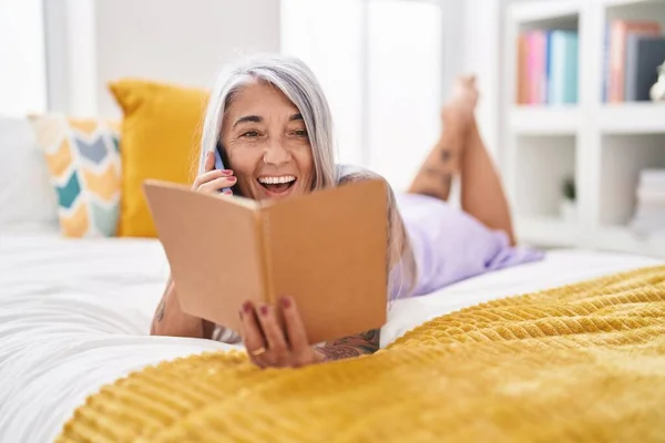 Middle Age Grey Haired Woman Talking Smartphone Reading Book Bedroom — Foto de Stock