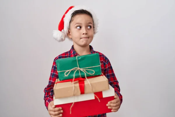 Pequeño Niño Hispano Con Sombrero Navidad Sosteniendo Regalos Sonriendo Mirando —  Fotos de Stock
